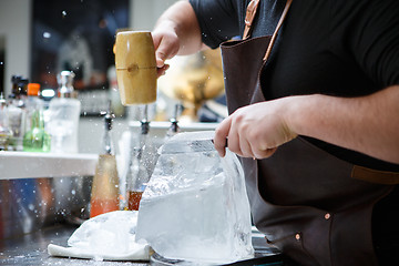 Image showing Bartender mannually crushed ice with wooden hammer and metal knife.