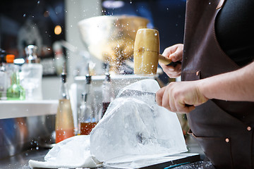 Image showing Bartender mannually crushed ice with wooden hammer and metal knife.