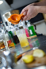 Image showing Bartender is straining cocktail in a glass