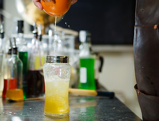 Image showing Bartender is straining cocktail in a glass