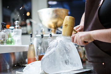 Image showing Bartender mannually crushed ice with wooden hammer and metal knife.