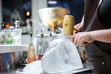 Image showing Bartender mannually crushed ice with wooden hammer and metal knife.