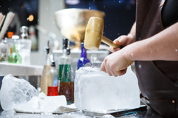 Image showing Bartender mannually crushed ice with wooden hammer and metal knife.