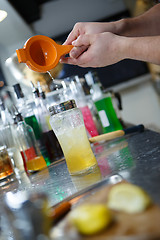 Image showing Bartender is straining cocktail in a glass