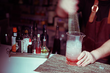 Image showing Bartender nixed cocktail in glass cup.