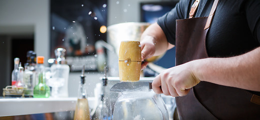 Image showing Bartender breaks ice with wooden hammer