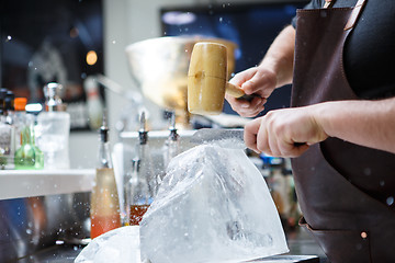 Image showing Bartender mannually crushed ice with wooden hammer and metal knife.