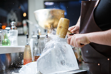 Image showing Bartender mannually crushed ice with wooden hammer and metal knife.