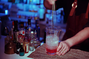 Image showing Bartender nixed cocktail in glass cup.