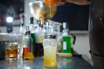 Image showing Bartender is straining cocktail in a glass