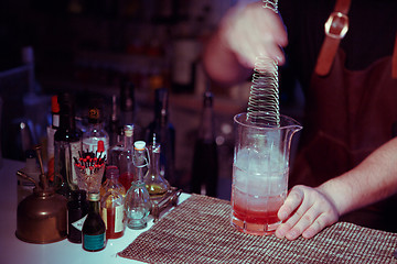 Image showing Bartender nixed cocktail in glass cup.