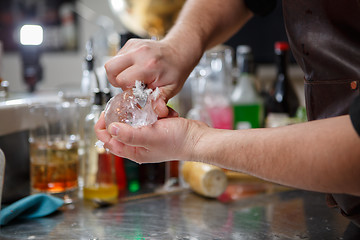 Image showing Bartender pours alcoholic drink into small glasses with flames