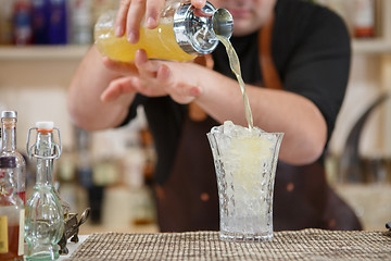 Image showing Bartender pouring cocktail into glass at the bar
