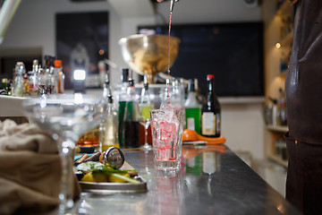 Image showing Bartender coocks cocktail behind a bar counter