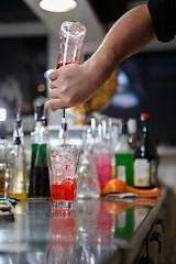 Image showing Bartender coocks cocktail behind a bar counter