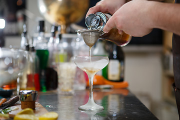 Image showing Bartender coocks cocktail behind a bar counter