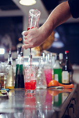 Image showing Bartender coocks cocktail behind a bar counter