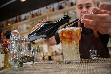 Image showing Bartender pouring cocktail into glass at the bar