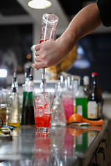 Image showing Bartender coocks cocktail behind a bar counter