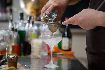 Image showing Bartender coocks cocktail behind a bar counter