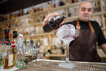 Image showing Bartender is pouring wine in the glass with giant ice, wide-angle image.