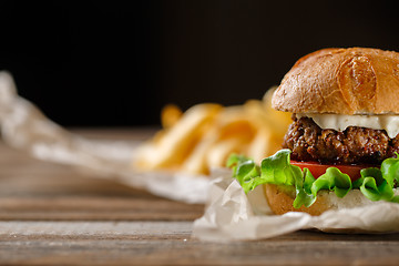 Image showing Homemade burger with french fries on wooden table