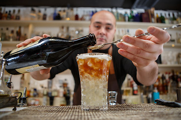 Image showing Bartender pouring cocktail into glass at the bar