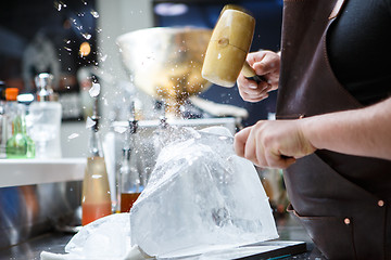 Image showing Bartender mannually crushed ice with wooden hammer and metal knife.