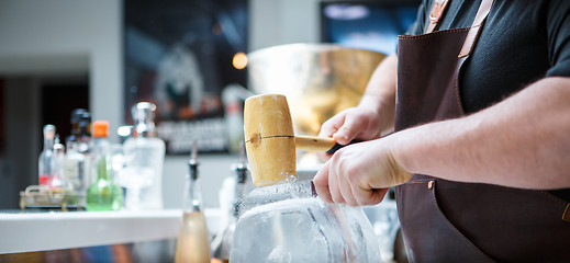 Image showing Bartender mannually crushed ice with wooden hammer and metal knife.