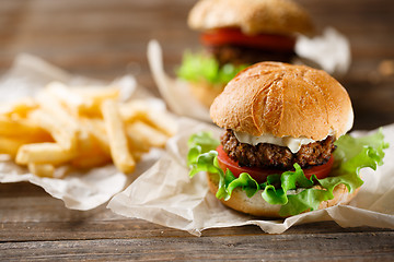 Image showing Homemade tasty burger and french fries on wooden table