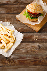 Image showing Homemade hamburgers and french fries on wooden table