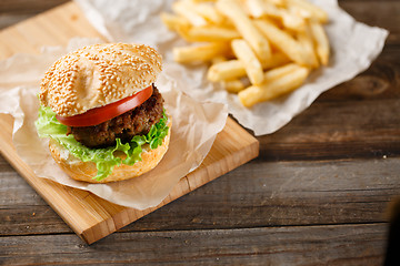 Image showing Homemade hamburgers and french fries on wooden table