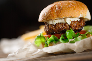 Image showing Homemade burger with french fries on wooden table