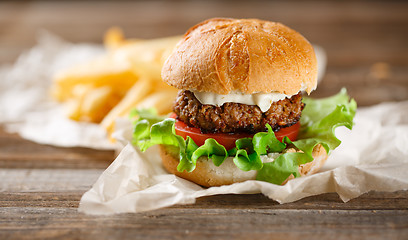 Image showing Homemade burger with french fries on wooden table