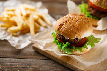 Image showing Homemade hamburgers and french fries on wooden table