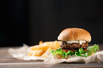 Image showing Homemade burger with french fries on wooden table