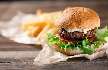 Image showing Homemade burger with french fries on wooden table