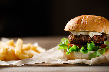 Image showing homemade burger and french fries on a wooden plate