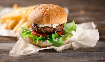 Image showing Homemade burger with french fries on wooden table