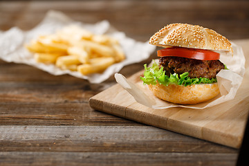 Image showing Homemade hamburgers and french fries on wooden table