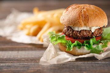 Image showing Homemade burger with french fries on wooden table