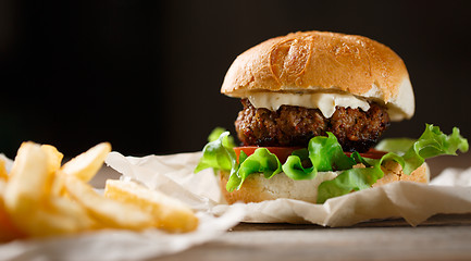 Image showing homemade burger and french fries on a wooden plate