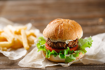 Image showing homemade burger and french fries on a wooden plate