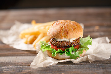 Image showing Homemade burger with french fries on wooden table