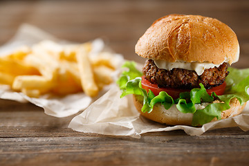 Image showing homemade burger and french fries on a wooden plate