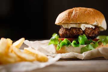 Image showing homemade burger and french fries on a wooden plate