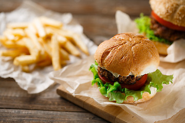 Image showing Homemade hamburgers and french fries on wooden table