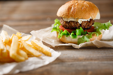 Image showing homemade burger and french fries on a wooden plate