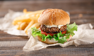 Image showing Homemade burger with french fries on wooden table