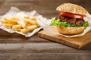 Image showing Homemade hamburgers and french fries on wooden table